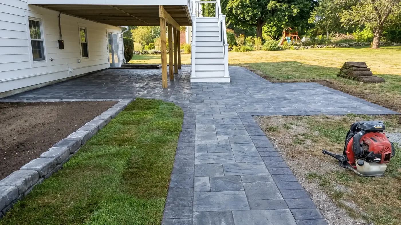 Close up of paver patio joints filled with polymeric sand being swept across the surface before watering